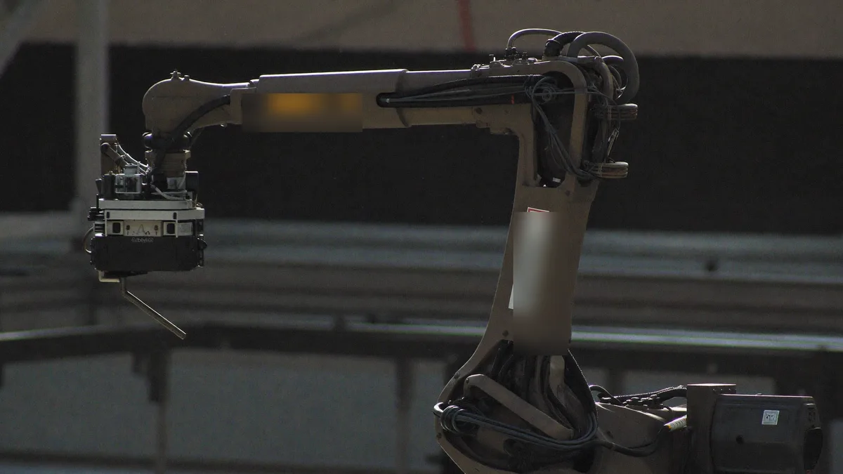 Braccio robotico industriale in controluce in una fabbrica in penombra