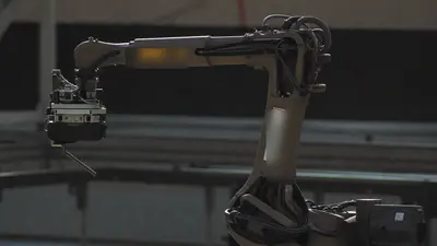 Braccio robotico industriale in controluce in una fabbrica in penombra